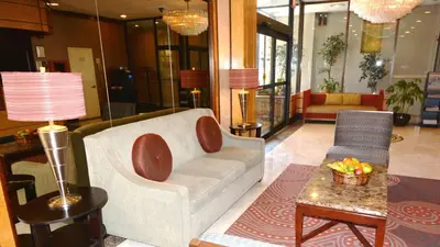 a lobby with a couch and a chair and a table at Adria Hotel and Conference Center in Queens