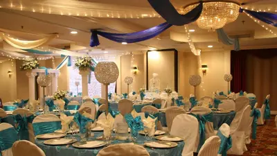 a banquet hall filled with tables and chairs with blue linens at Adria Hotel and Conference Center in Queens