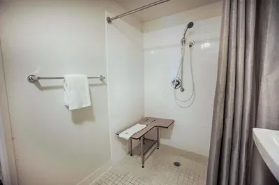 a bathroom with a shower and a table in it at Motel 6-Albany, NY in Albany