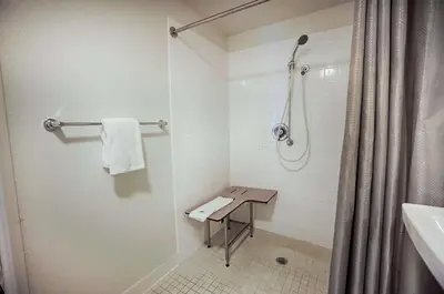 a bathroom with a shower and a bench in it at Motel 6-Albany, NY in Albany