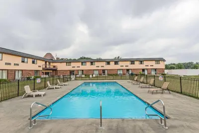 a swimming pool with chairs and a building at Days Inn by Wyndham Berlin Meriden in Berlin