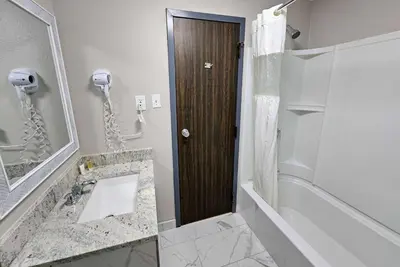 a bathroom with a shower and a wooden door at Days Inn by Wyndham Berlin Meriden in Berlin