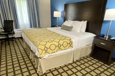 a hotel room with a large bed with a brown headboard at Baymont by Wyndham Latham Albany Airport in Latham