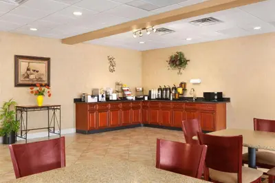 a waiting room with a counter and a table and chairs at Baymont by Wyndham Latham Albany Airport in Latham