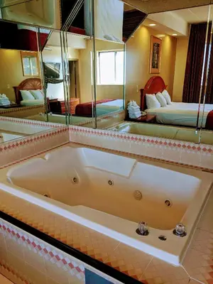 a large bath tub in a room with two beds at Jets Motor Inn in Queens
