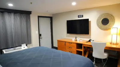 a bedroom with a bed and a desk and a television at Carrier Motor Lodge in Newington