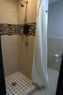 a bathroom with a shower with a tiled shower at Carrier Motor Lodge in Newington