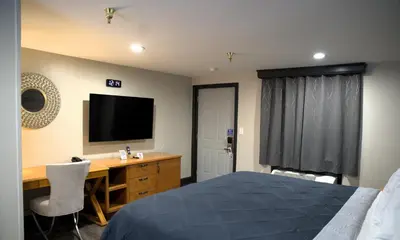 a bedroom with a bed and a desk with a television at Carrier Motor Lodge in Newington