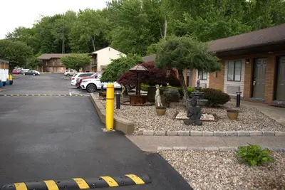 a parking lot with a statue in front of a building at Carrier Motor Lodge in Newington