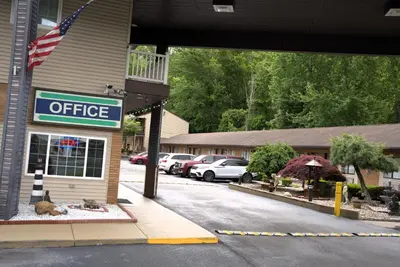 a office sign in front of a building with cars parked at Carrier Motor Lodge in Newington