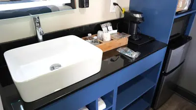 a bathroom with a white sink and blue cabinets at Carrier Motor Lodge in Newington