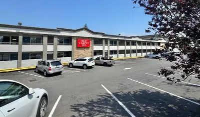 a parking lot with cars parked in front of a building at Red Carpet Inn - Stamford in Stamford
