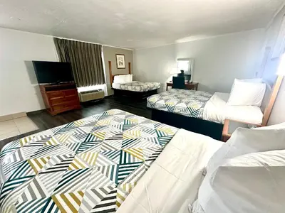 a hotel room with two beds and a television at Red Carpet Inn - Stamford in Stamford