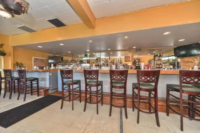 a bar with wooden stools in a restaurant at Red Carpet Inn - Stamford in Stamford
