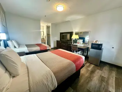 a hotel room with two beds and a desk at Red Carpet Inn Norwalk in Norwalk