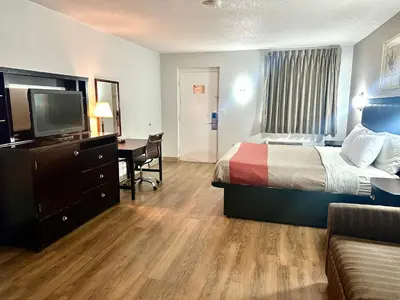 a hotel room with a bed and a desk and a television at Red Carpet Inn Norwalk in Norwalk