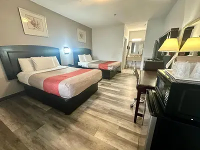 a hotel room with two beds and a desk at Red Carpet Inn Norwalk in Norwalk