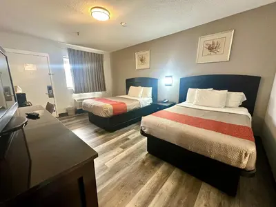 a hotel room with two beds and a desk at Red Carpet Inn Norwalk in Norwalk