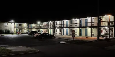 a building with cars parked in a parking lot at night at Red Carpet Inn Norwalk in Norwalk