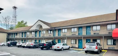 a large building with cars parked in a parking lot at Red Carpet Inn Norwalk in Norwalk