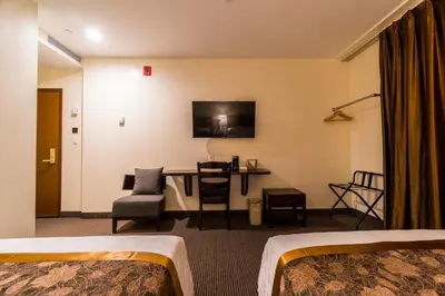 a hotel room with two beds and a desk at John Hotel in Queens