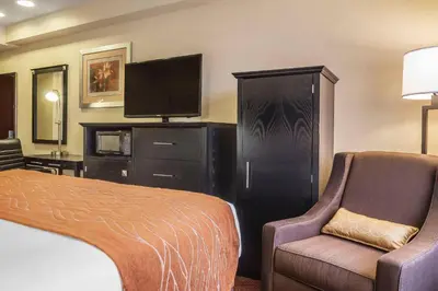 a hotel room with a bed and a chair and a tv at Comfort Inn & Suites LaGuardia Airport in Queens