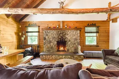 a living room with a stone fireplace in a log cabin at Roscoe Retreat in Roscoe