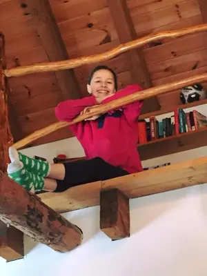 a woman sitting on top of a wooden bed at Roscoe Retreat in Roscoe