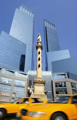 a yellow taxi driving past a statue in a city at Mandarin Oriental, New York in New York