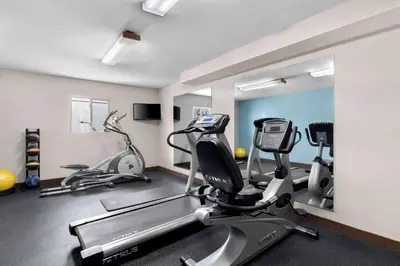 a gym with treadmills and ellipticals in a room at Days Inn by Wyndham Albany SUNY in Albany