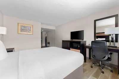 a hotel room with a bed and a desk and a chair at Days Inn by Wyndham Albany SUNY in Albany