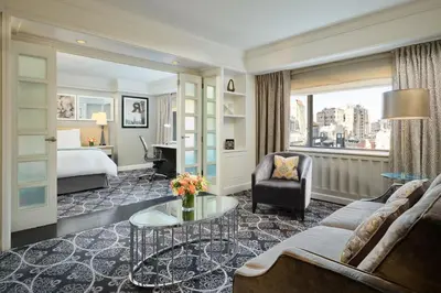 a hotel room with a bed and a couch and a table at Loews Regency New York Hotel in New York