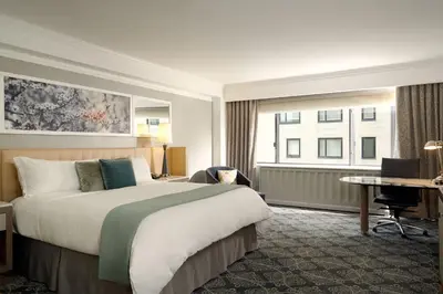 a hotel room with a large bed and a desk at Loews Regency New York Hotel in New York