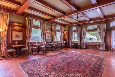 a dining room with tables and chairs and windows at Wilburton Inn in Manchester
