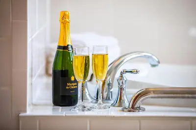 a bottle of champagne and two glasses on a sink at Wilburton Inn in Manchester