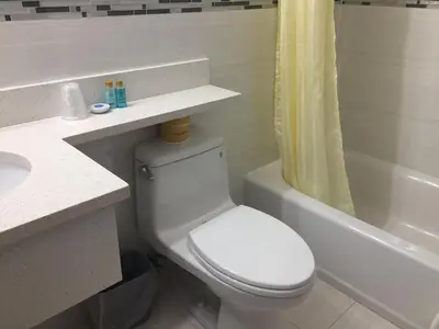 a bathroom with a toilet and a sink and a tub at The Queens Hotel in Queens