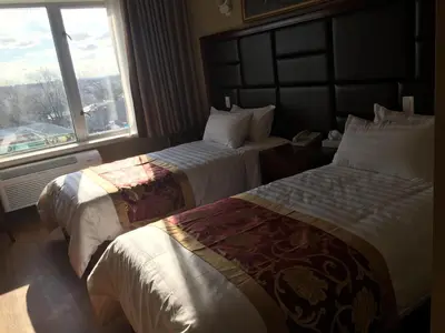 a hotel room with two beds and a window at The Queens Hotel in Queens
