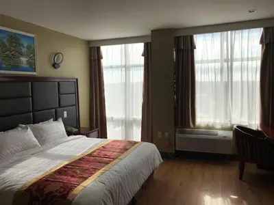 a bedroom with a large bed and large windows at The Queens Hotel in Queens