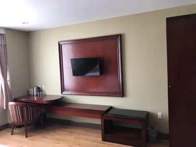 a room with a desk and a tv on the wall at The Queens Hotel in Queens