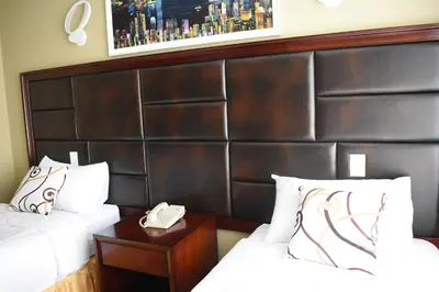 a hotel room with two beds and a wooden headboard at The Queens Hotel in Queens