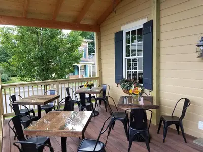 a patio with tables and chairs on a porch at The Railroad Inn in Cooperstown