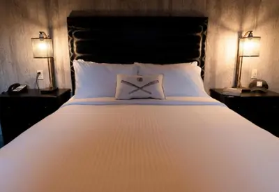 a large white bed with a bow pillow on it at The Railroad Inn in Cooperstown