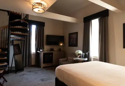 a bedroom with a bed and a tv and a chair at The Railroad Inn in Cooperstown