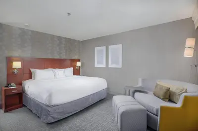 a hotel room with a bed and a chair at Courtyard by Marriott New Haven Orange in Orange