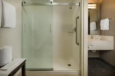 a shower with a glass door in a bathroom at Courtyard by Marriott New Haven Orange in Orange