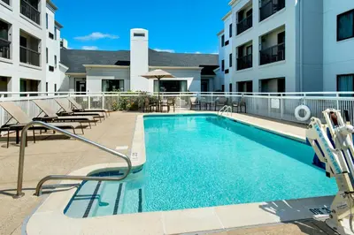 a swimming pool with chairs and a building at Courtyard by Marriott New Haven Orange in Orange