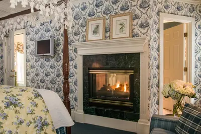 a bedroom with a fireplace with blue and white wallpaper at The INN at Ormsby Hill in Manchester