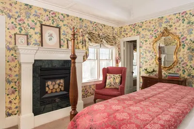 a bedroom with a bed and a fireplace and a chair at The INN at Ormsby Hill in Manchester