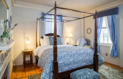 a bedroom with a canopy bed with a blue comforter at Daniel Stebbins B and B in South Hadley