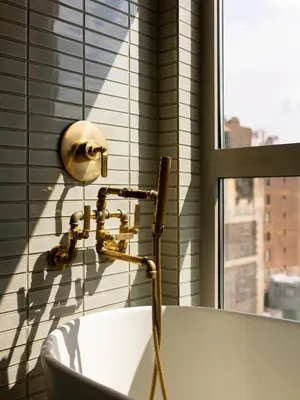 a bathroom with a bath tub with a shower head at MADE Hotel in New York